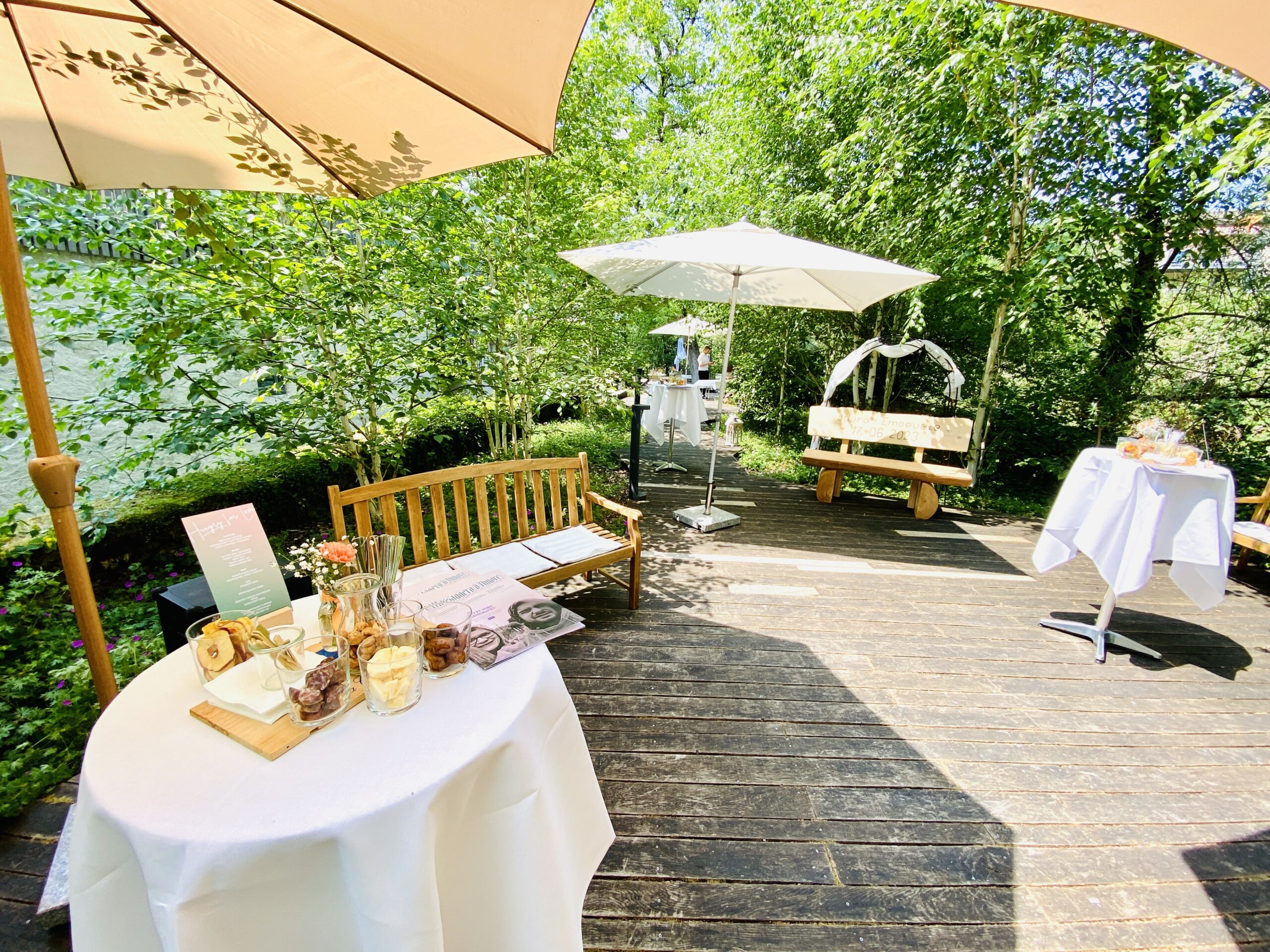 Apéro auf dem Holzdeck der Insel im Mühlerama Seon mit Stehtischen, Sonnenschirm und Holzbänken