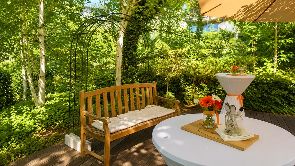 Gartenbank und Stehtisch mit Blumen auf der Insel im Mühlerama Seon