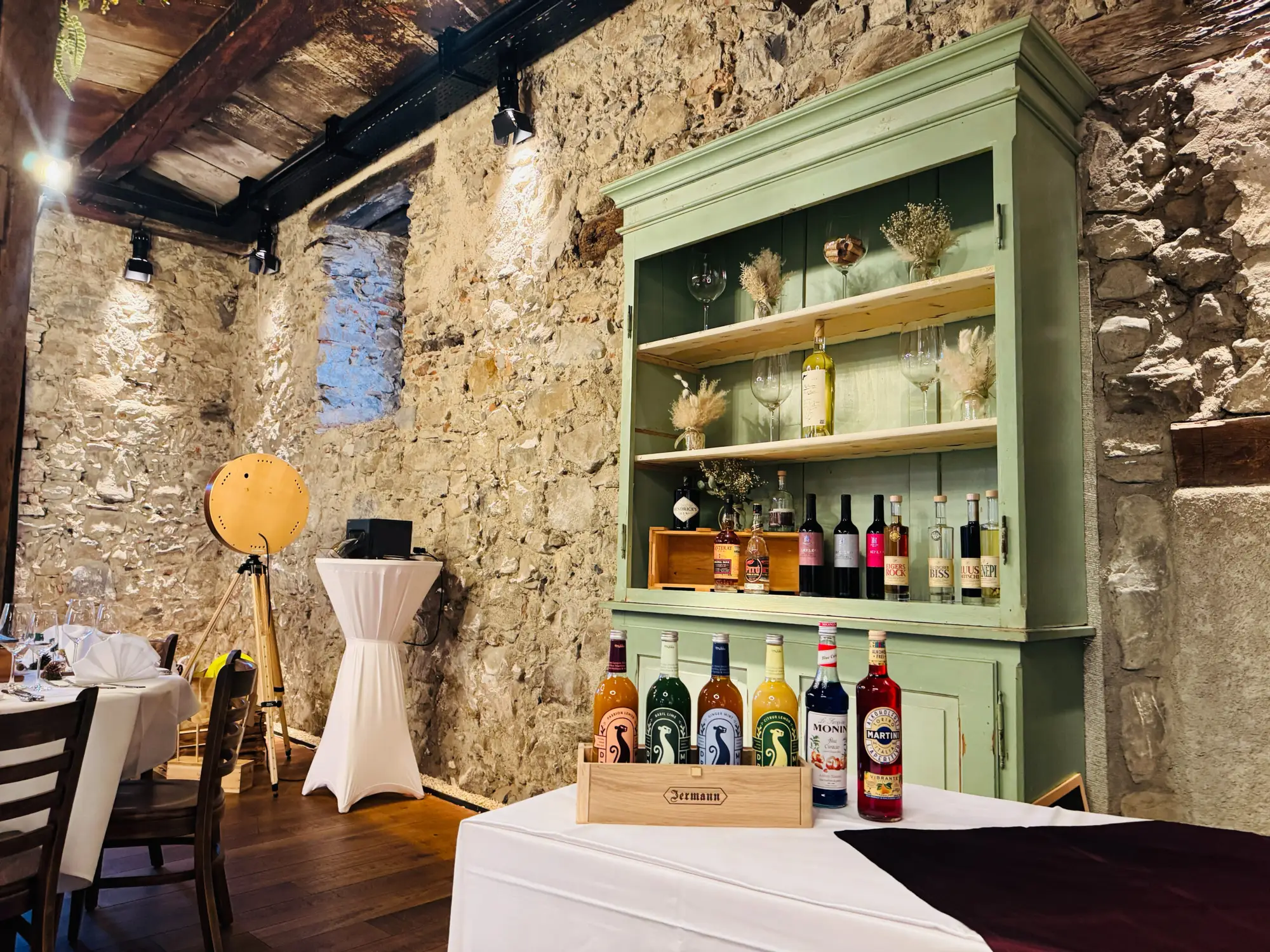 Bar mit Flaschen und Gläsern vor der Natursteinwand im Mühlerama Seon