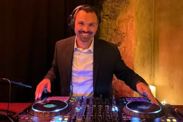 Hochzeits-DJ am Mischpult mit Kopfhörern vor einer Steinwand
